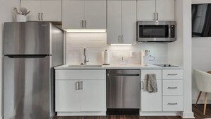 Una cocina moderna con electrodomésticos de acero inoxidable, armarios blancos y un microondas integrado.