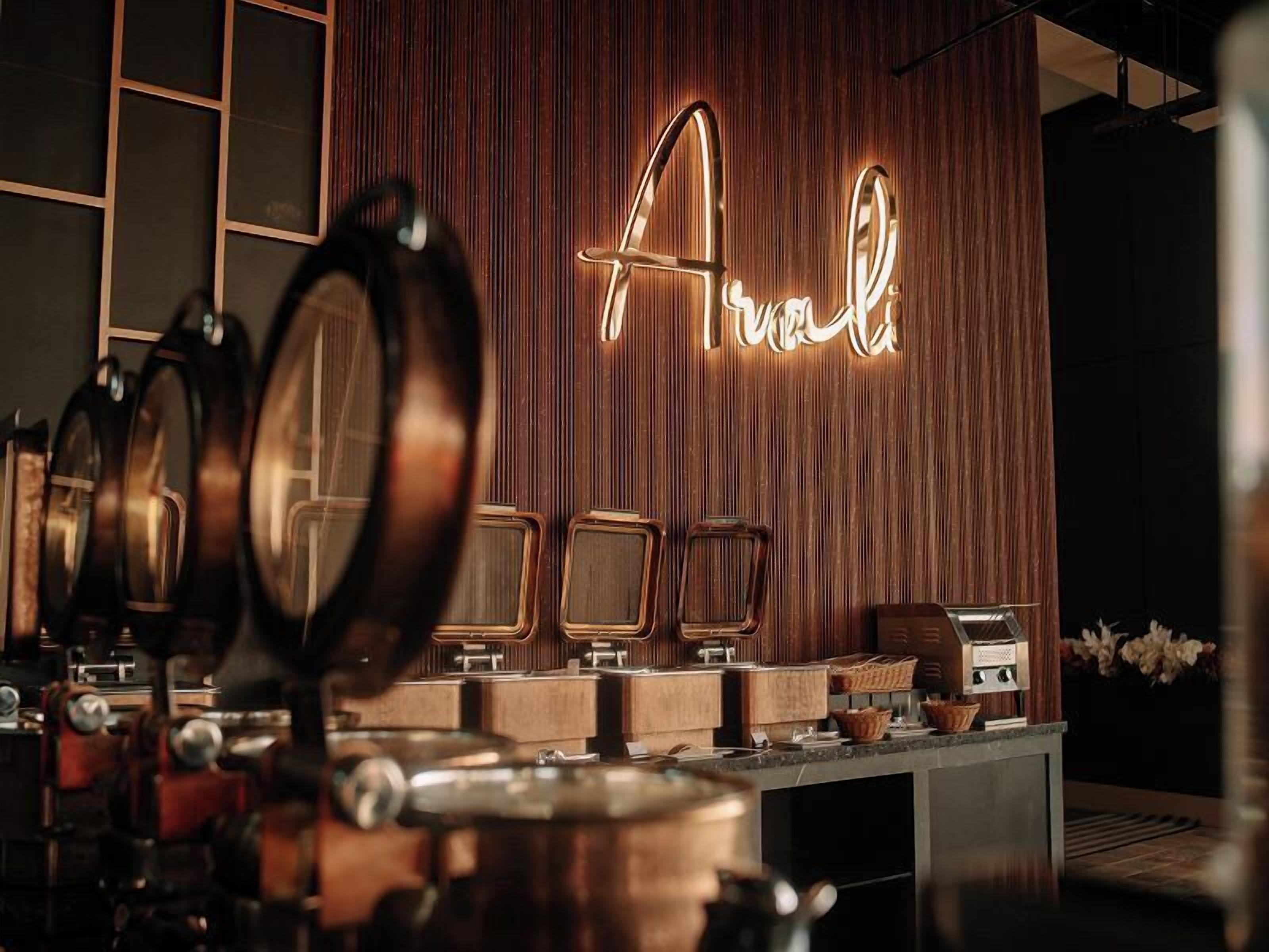 A bar area with a neon sign reading "Arnal," a coffee machine, and a counter with various items.