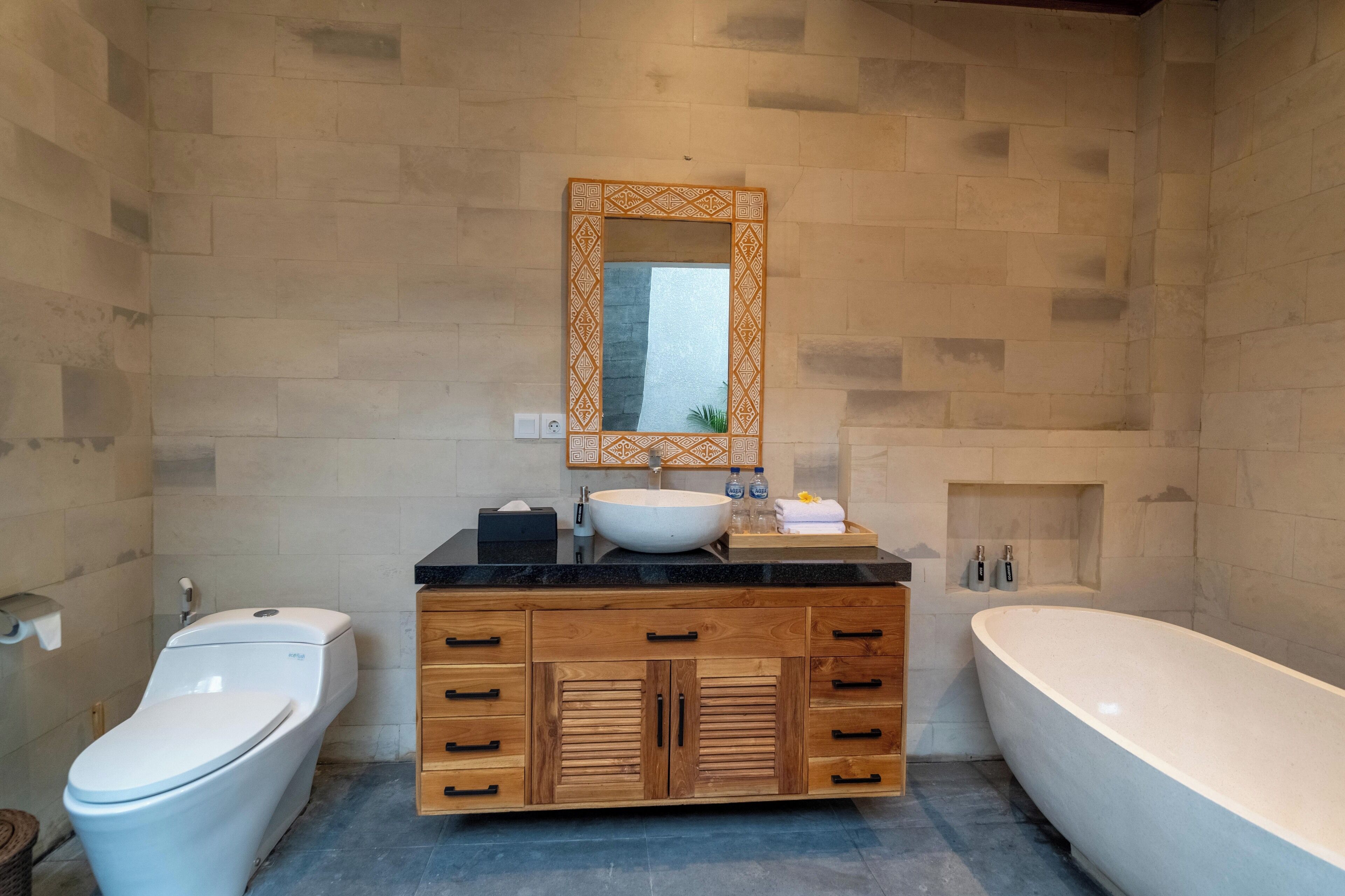 Un baño moderno con un inodoro independiente, un tocador de madera con lavabo y una bañera.