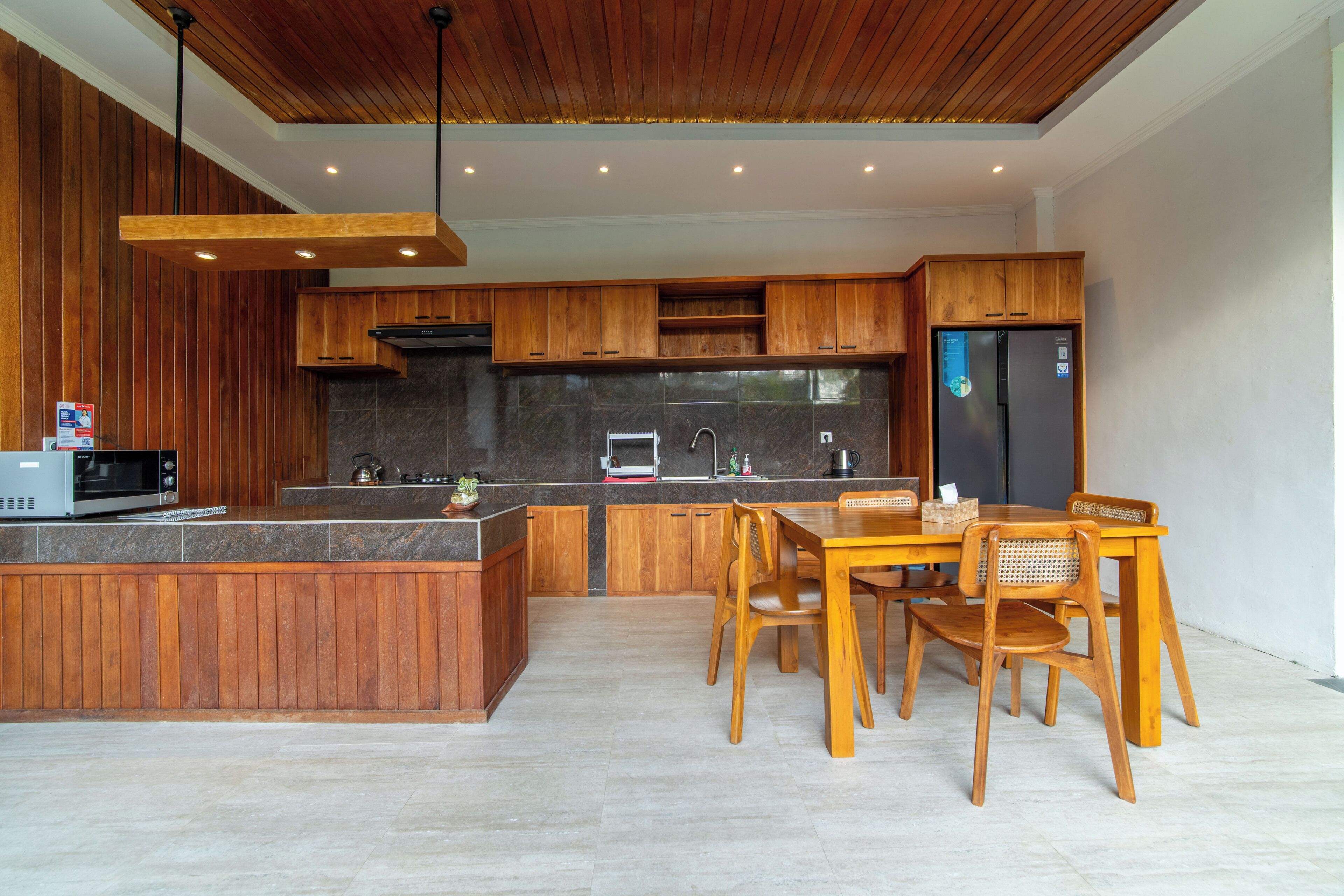 Eine moderne Küche mit Holzschränken, einer zentralen Kochinsel und einem Essbereich mit Holzkästen.