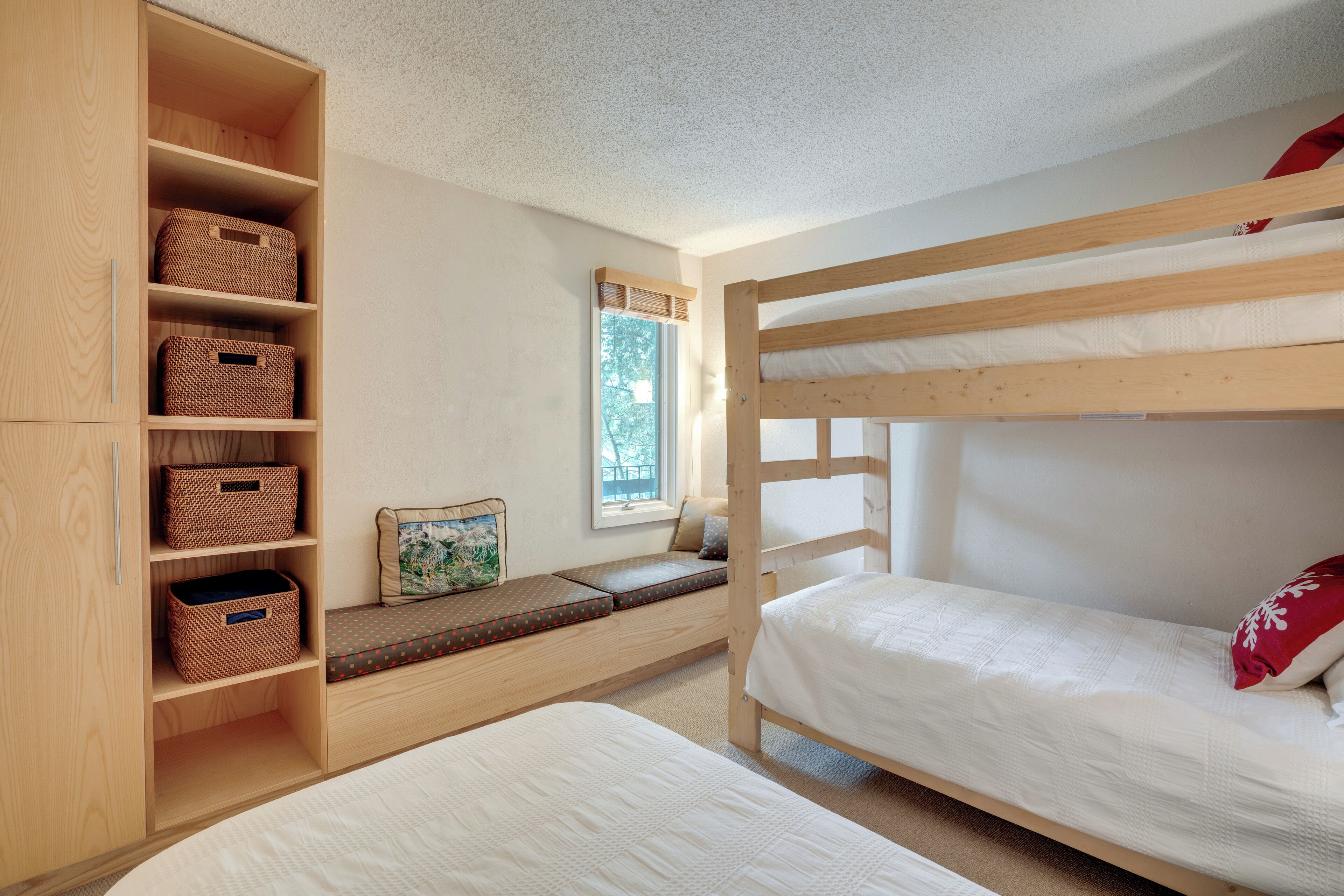 Ein Schlafraum mit Etagenbetten, einem Holzschrank und fest eingebauten Regalen.