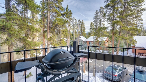 Un balcón con una parrilla, con vistas a una calle nevada y casas.