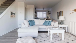 A modern living room with a white sectional sofa, a coffee table, and a patterned rug. - Beautifully Refurbished 4-Bed Beachside Retreat (Selsey)