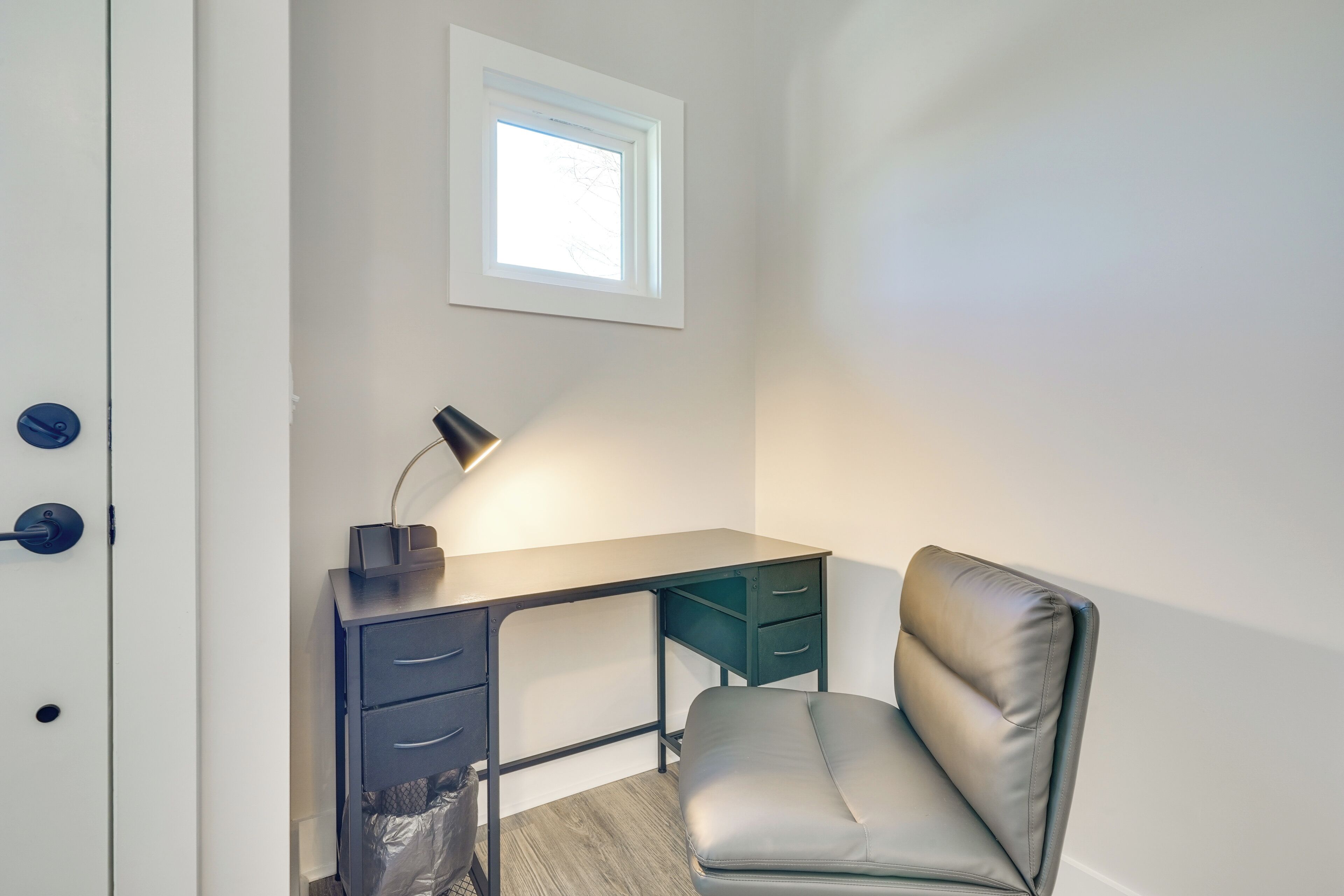 Una habitación pequeña con escritorio, silla y un ventanal.