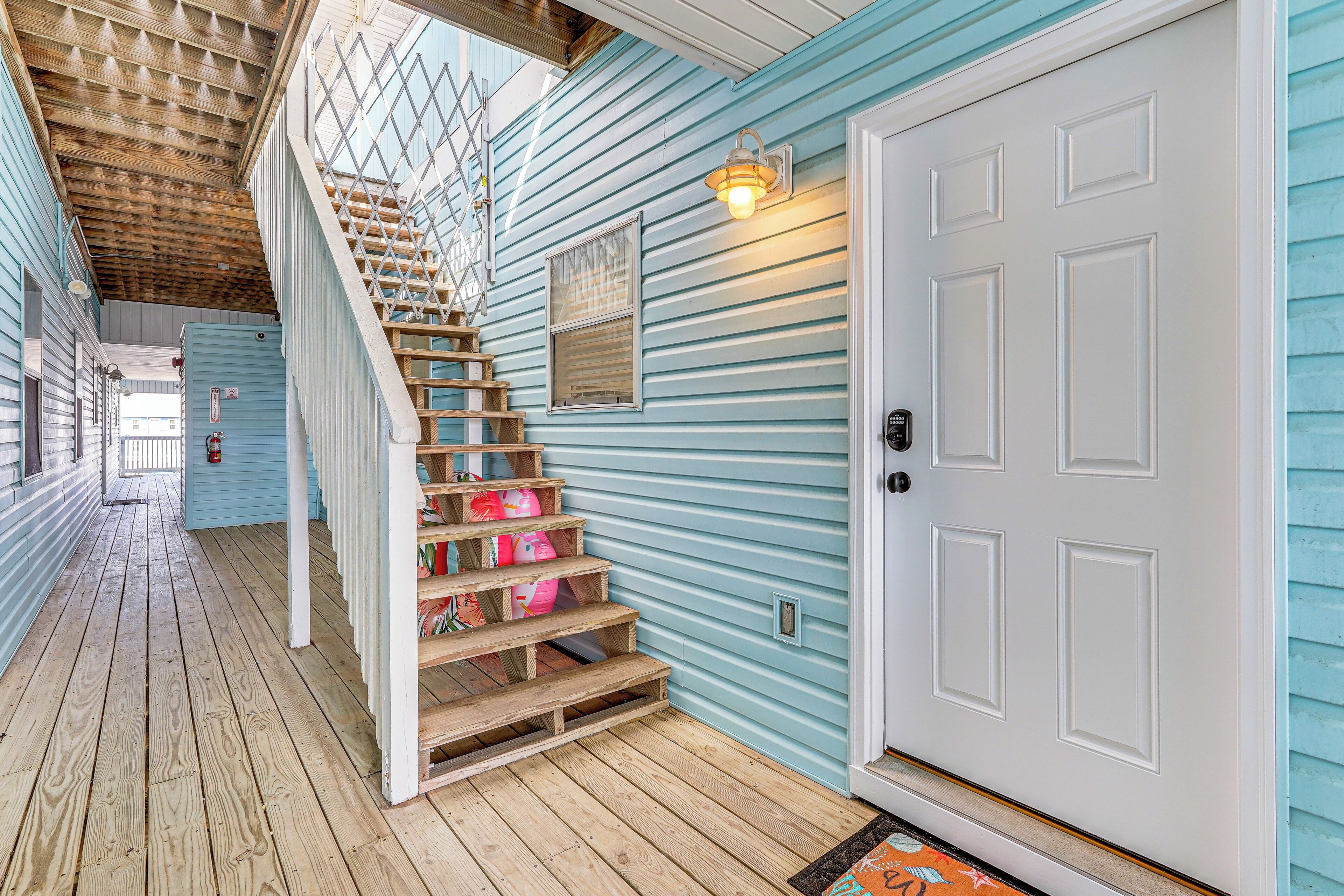 A wooden staircase leading to a white door with a light fixture above it.