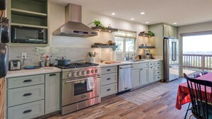 Una cucina moderna con elettrodomestici integrati, un'area pranzo con tovaglia rossa e vista sull'esterno.