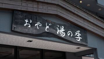 A building with a sign that reads "おやすみの亭" in white characters on a black background.