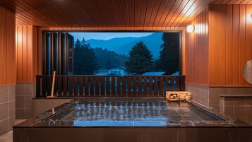 A hot tub with a wooden deck and a view of mountains.
