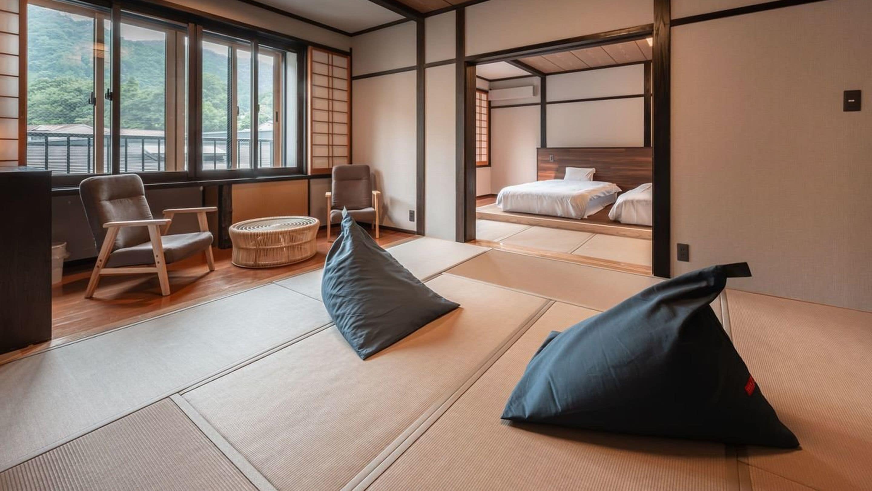 Ein traditioneller japanischer Raum mit Tatami-Boden, einem Bett, einem Schreibtisch und Blick auf einen Berg.