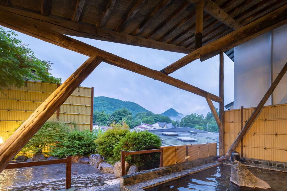 A traditional Japanese onsen with wooden beams and a view of mountains.