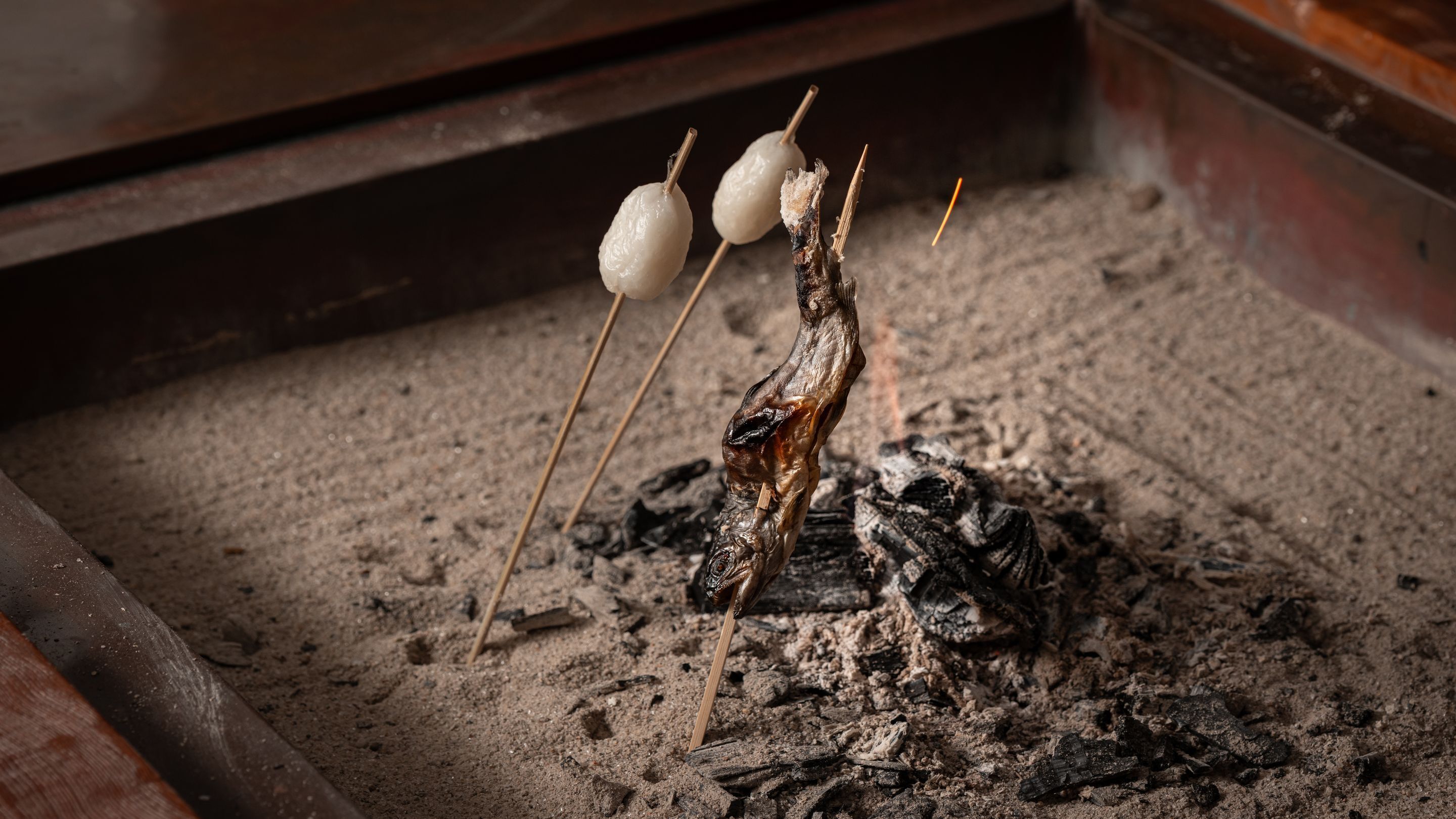 Un gril avec des brochettes de nourriture cuites sur une flamme nue.