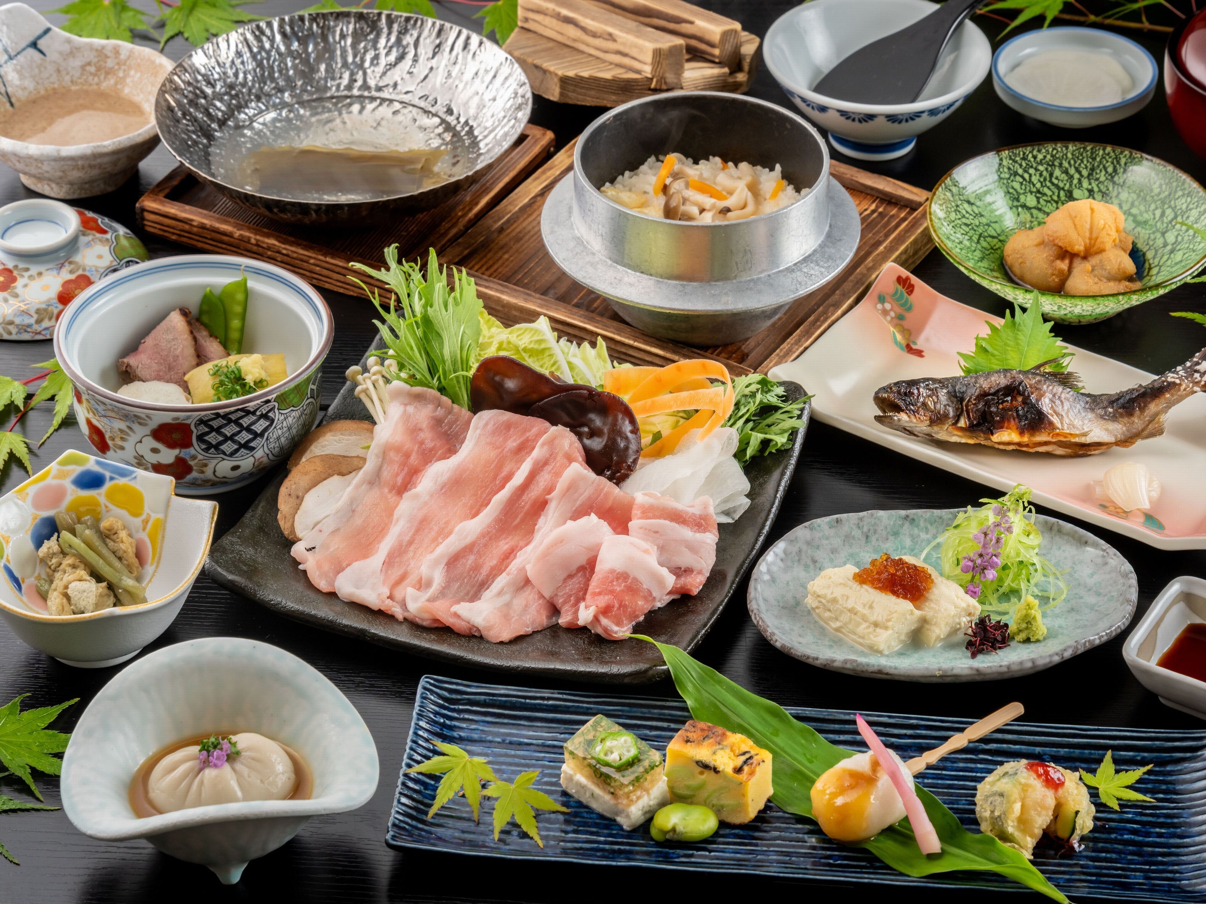 A variety of Japanese dishes including sashimi, tempura, and sushi, arranged on a wooden table.