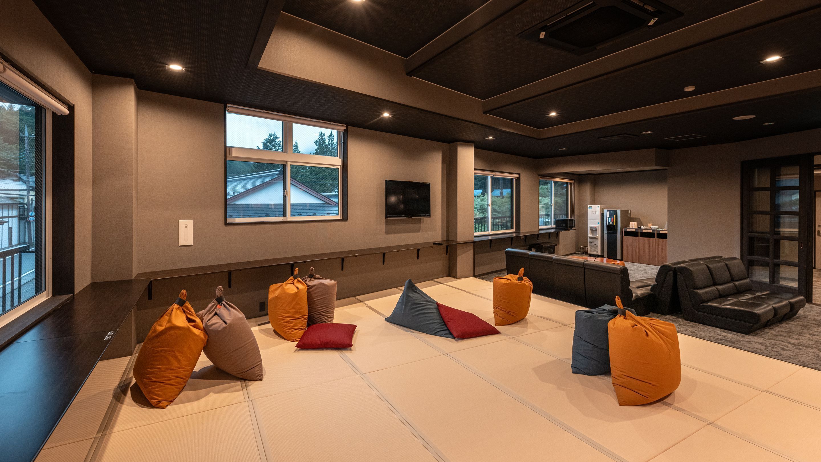 A modern hotel room with tatami mats, a sofa, and a television on the wall.