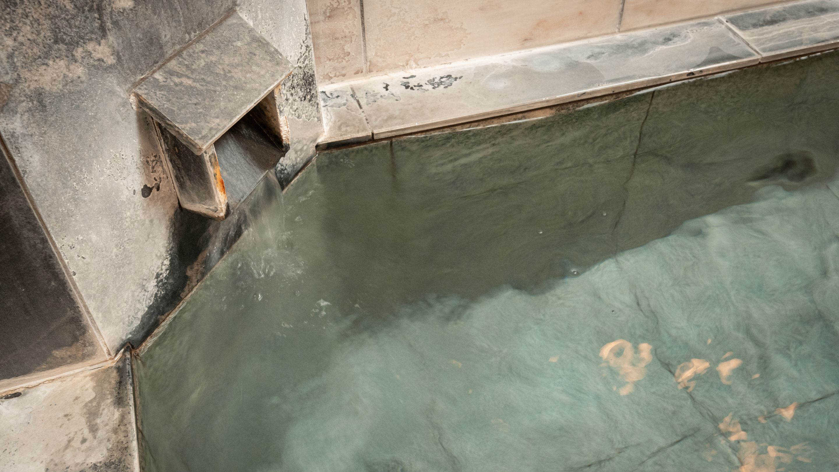 Parte de una piscina con borde de azulejos y un desagüe visible.