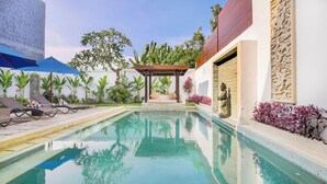 Une piscine avec des chaises longues et une pergola.