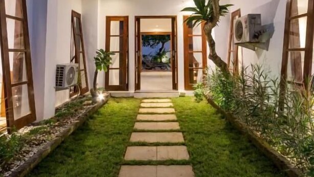 Une maison moderne dotée d’un chemin central, d’une verrière et offrant une vue sur l’extérieur.