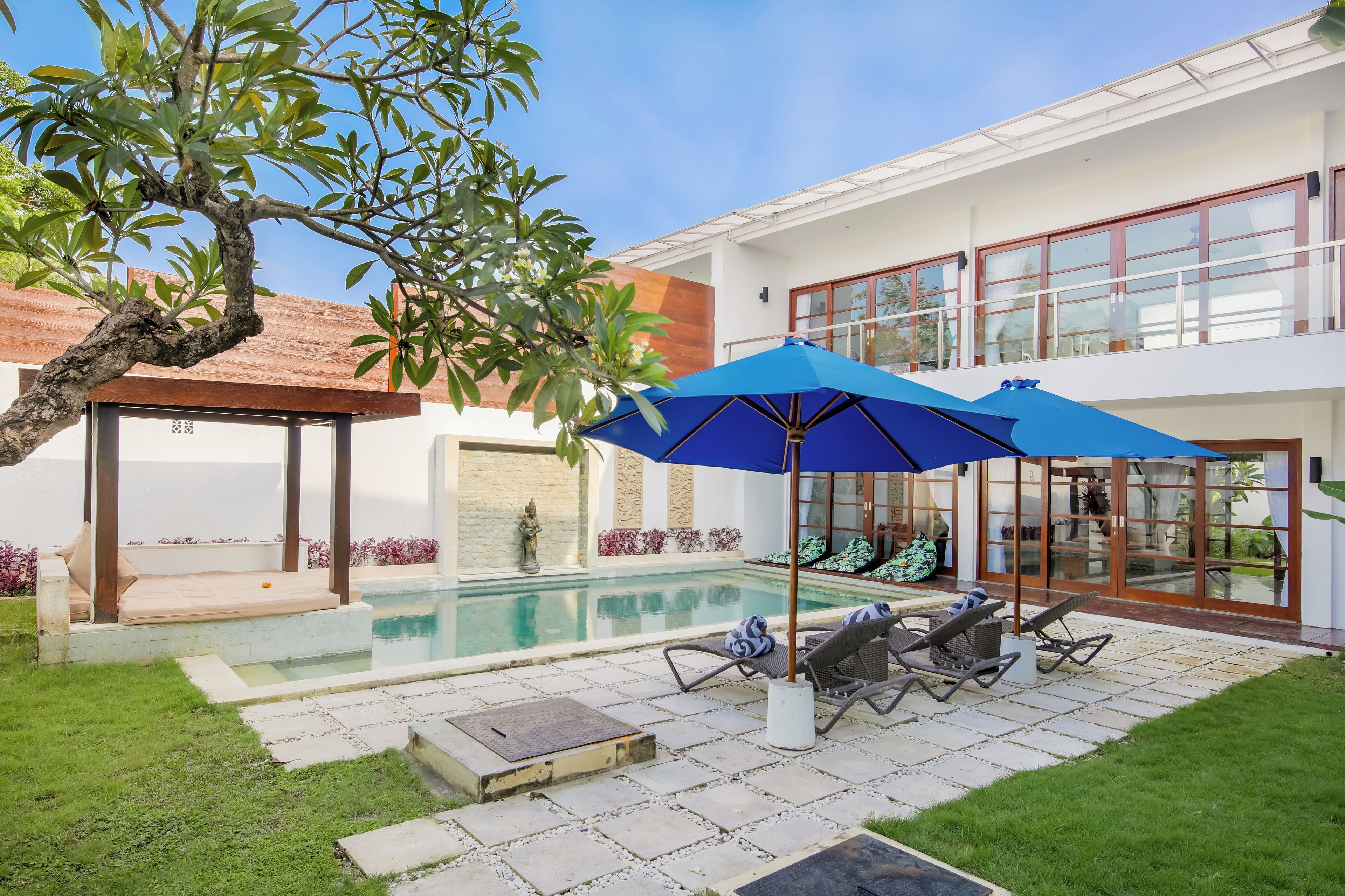 A modern house with a swimming pool, outdoor seating, and a covered patio area.