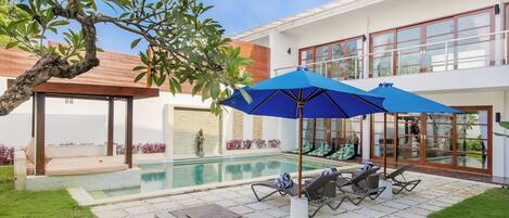 A modern house with a swimming pool, outdoor seating, and a covered patio area.