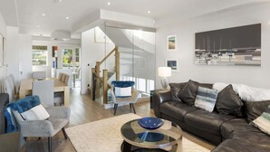 A modern living room with a leather sofa, a glass coffee table, and a dining area with a wooden table and chairs. - Bright & Modern Townhouse, Private Parking (Cornwall)