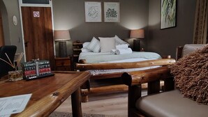 A hotel room with a wooden bed, a desk with a calculator and books, a chair, and a large window. - Indulgent Escape, Jet Bath, Stunning Views & Boma Firepit -Retreat from the City (Roodepoort)