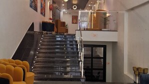 A modern lobby with a marble floor, a staircase, and a central chandelier. - BlueNeck Ayodhya-Near ShriRam Mandir (Faizabad)