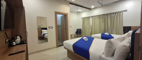 A hotel room with two beds, a TV, a mirror, a desk, and a chair.