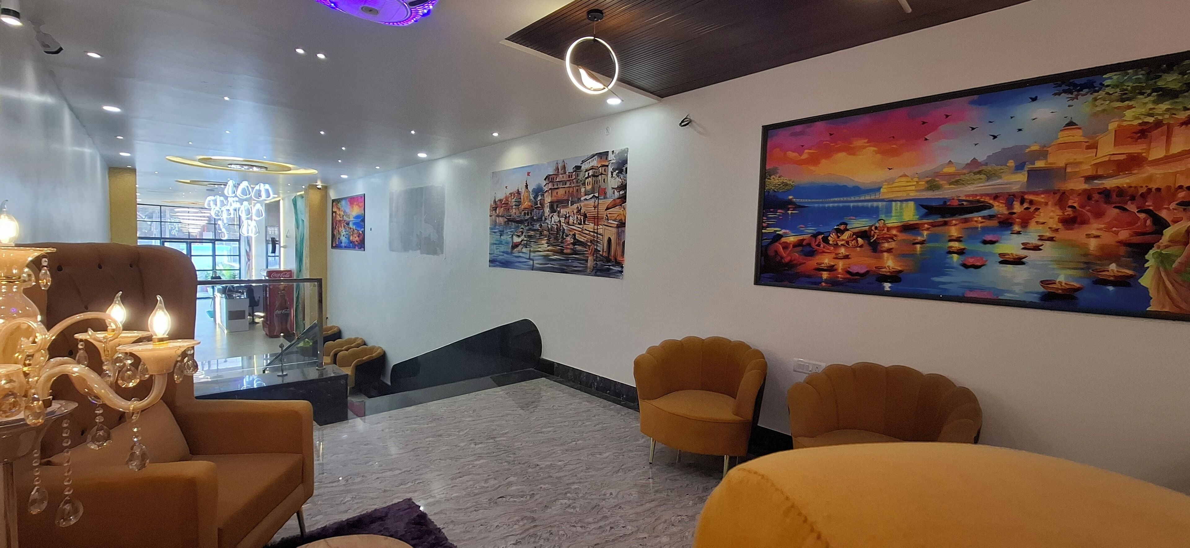 A modern hotel lobby with comfortable seating, artwork on the walls, and a chandelier.