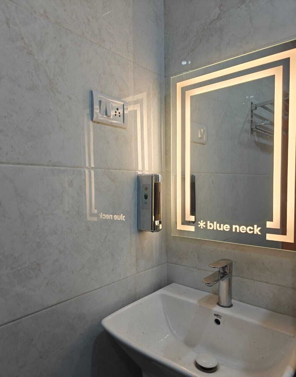 A bathroom with a white sink, a mirror with a light frame, and a towel rack.