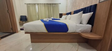 A modern hotel room with a large bed, wooden headboard, and a small wooden bench.