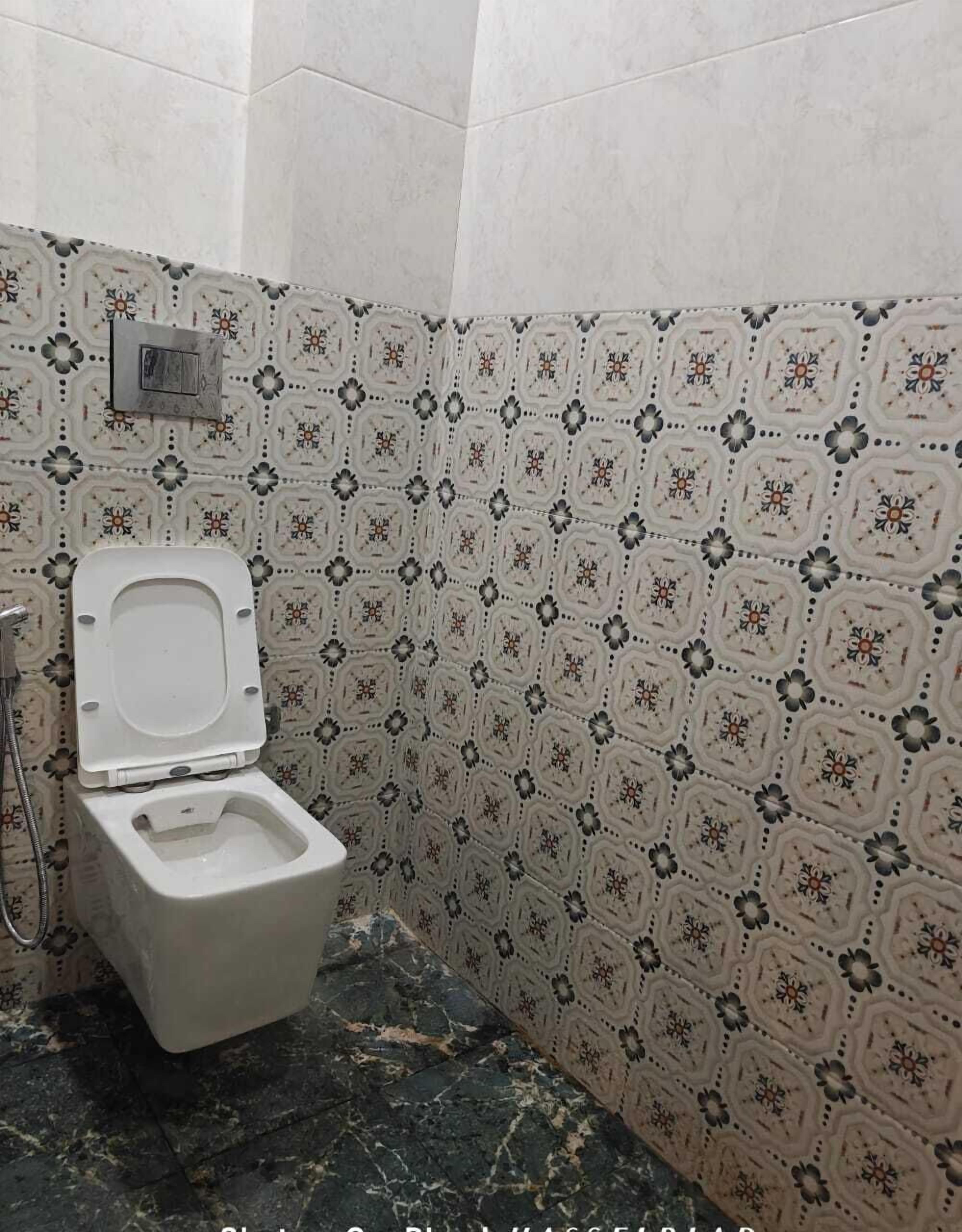 Un baño con inodoro, ducha y azulejos estampados en las paredes.