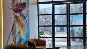A modern lobby with a large window, a decorative wall with feather art, and a unique ceiling light fixture. - BlueNeck Ayodhya-Near ShriRam Mandir (Faizabad)