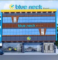 Un hotel moderno con un llamativo logotipo en azul, grandes ventanales y una entrada despejada.