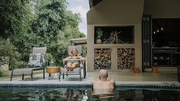 Una piscina al aire libre, sillones reclinables de piscina