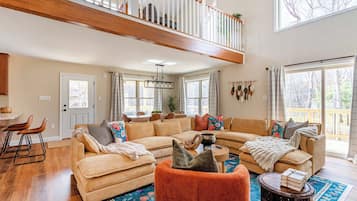 A spacious living room with a large sectional sofa, a coffee table, and a staircase leading to an upper level.