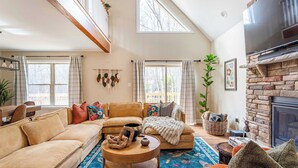 A cozy living room with a large sofa, a fireplace, and a dining area.