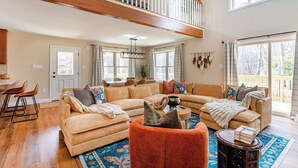 A spacious living room with a large sectional sofa, a coffee table, and a staircase leading to an upper level.