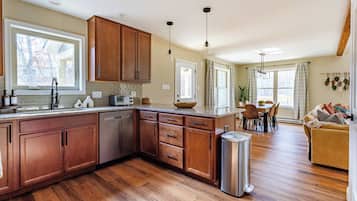 Una cocina amplia con armarios de madera, lavavajillas y un comedor con mesa y sillas.