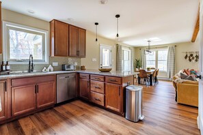 A spacious kitchen with wooden cabinets, a dishwasher, and a dining area with a table and chairs.