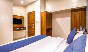 Quarto de hotel moderno com uma cama grande, guarda-roupa de madeira e televisão na parede.