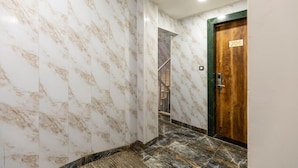 Un couloir aux murs de marbre et une porte en bois portant le numéro 206.