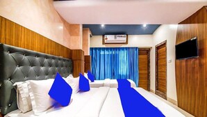 Une chambre d’hôtel avec un grand lit, un téléviseur à écran plat et un climatiseur mural.