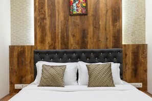 A bed with a tufted headboard, white bedding, and two patterned pillows. - Hotel Suites Inn (Mumbai)