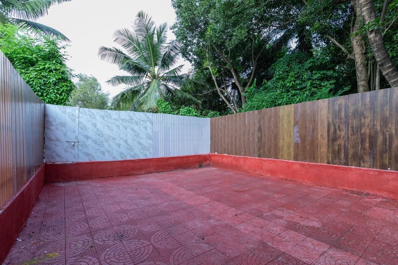 A courtyard with a red tiled floor, a white wall with a textured pattern, and a wooden wall with a reddish-brown finish.