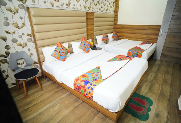 Habitación de hotel con cama doble, una silla y suelo de madera.