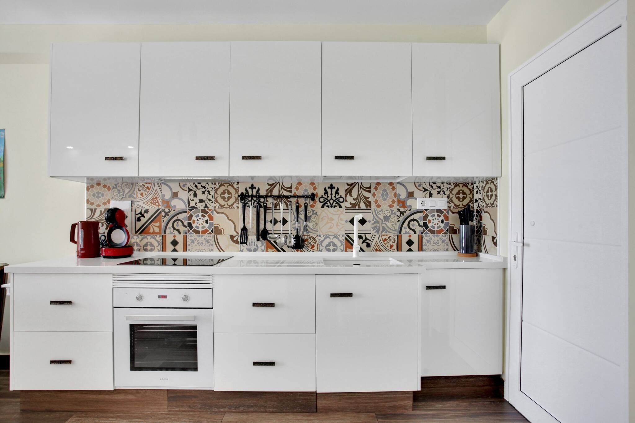 A modern kitchen with white cabinetry, a patterned backsplash, and a built-in oven.