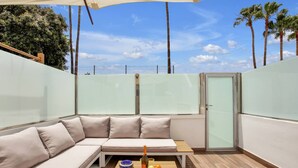 A modern outdoor seating area with a cushioned bench, a table with fruits and a bottle, and a glass door. - CASA DEL SOL, Beautiful Terrace, Fast Wi-Fi, Pool (COSTA ADEJE)