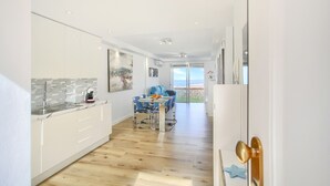 A modern kitchen with white cabinets, a tiled backsplash, and a dining area with blue chairs and a table. - The Penthouse, Fabulous Sunset, Heated Pool, Fiber (Costa Adeje)