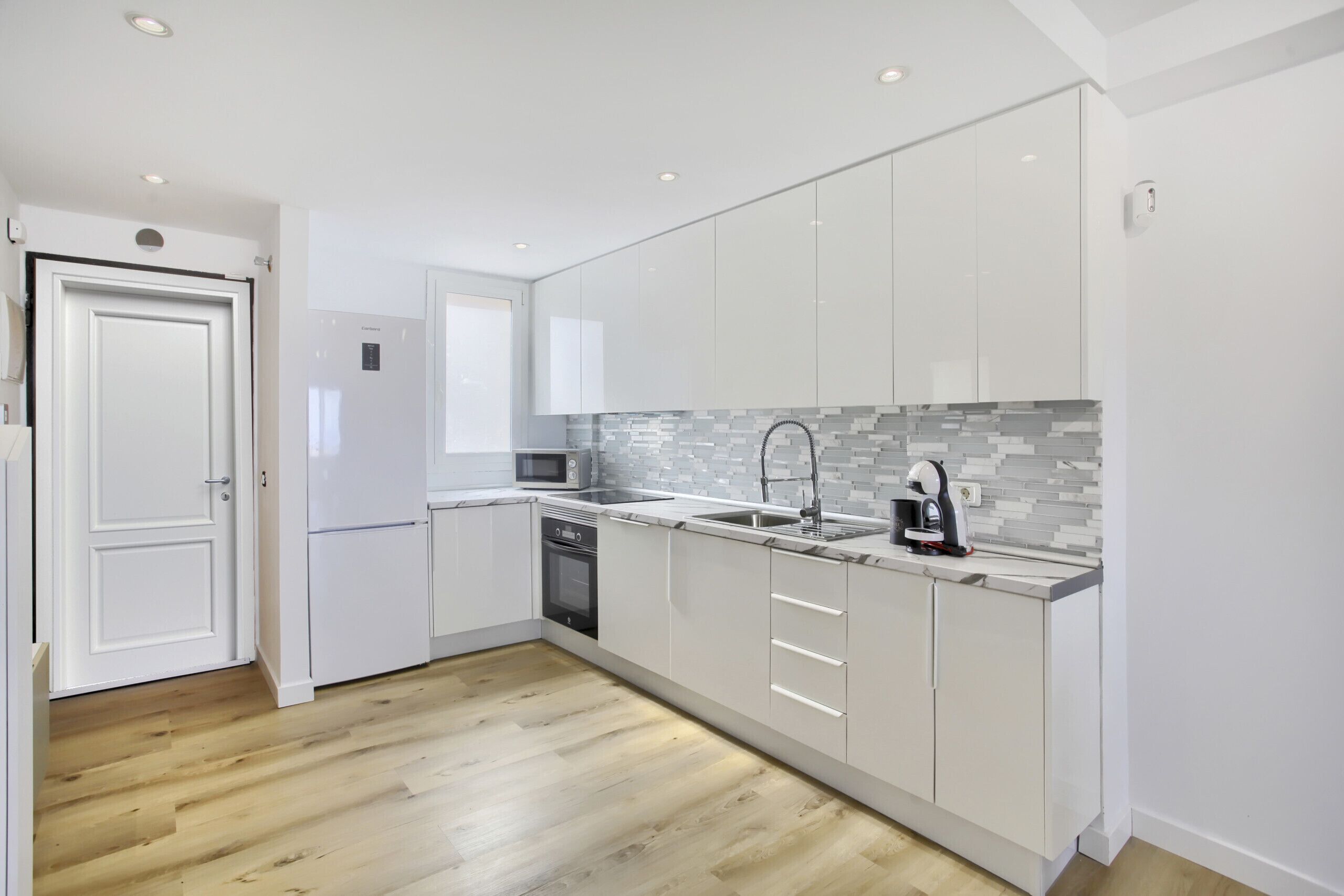 A modern kitchen with white cabinets, a granite countertop, and a tiled backsplash.