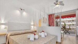 A modern hotel room with a large bed, a ceiling fan, and a balcony with a table and chairs. - Ocean Touch Studio, Pool, Wi-Fi, Near the Beach (Playa de Las Americas)