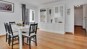 A dining area with a white table and chairs, a white cabinet with glass doors, and a framed picture on the wall.